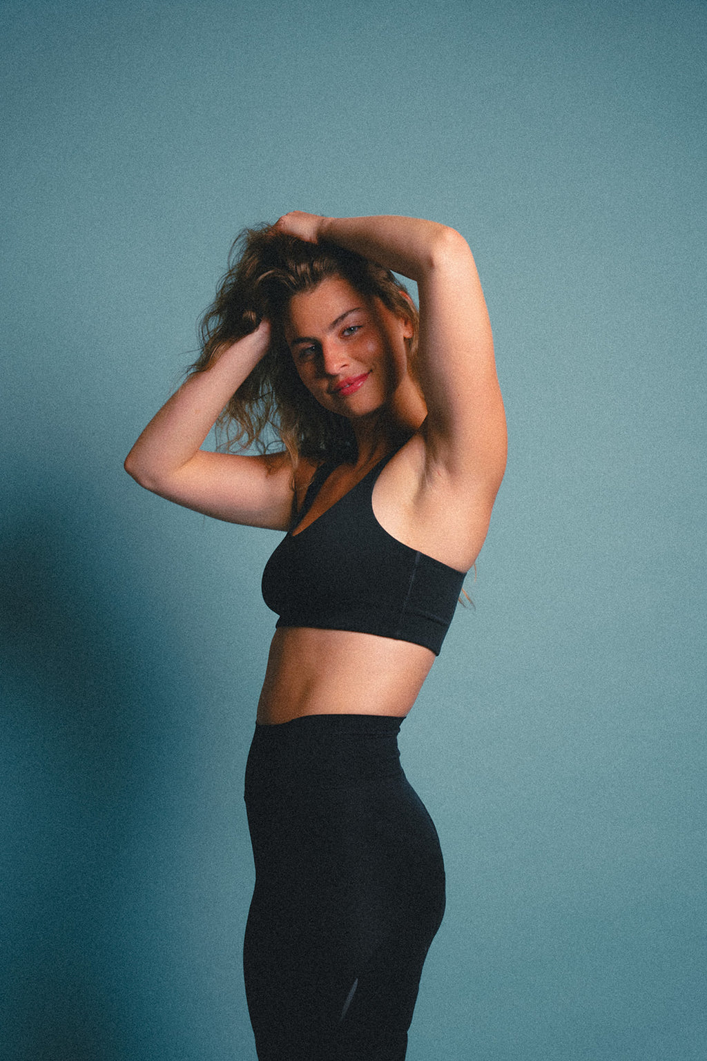 Woman wearing a black sports bra and cycling shorts against a blue background.