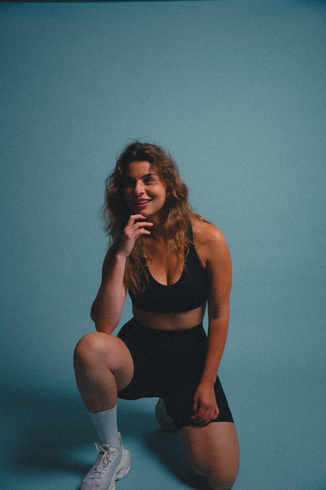 Woman in black cycling apparel posing against a blue background.