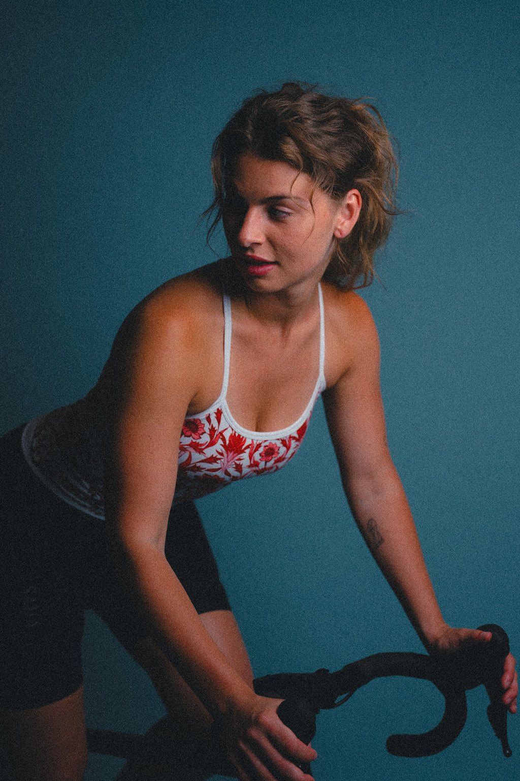 Woman wearing a colorful cycling jersey on a stationary bike against a blue background
