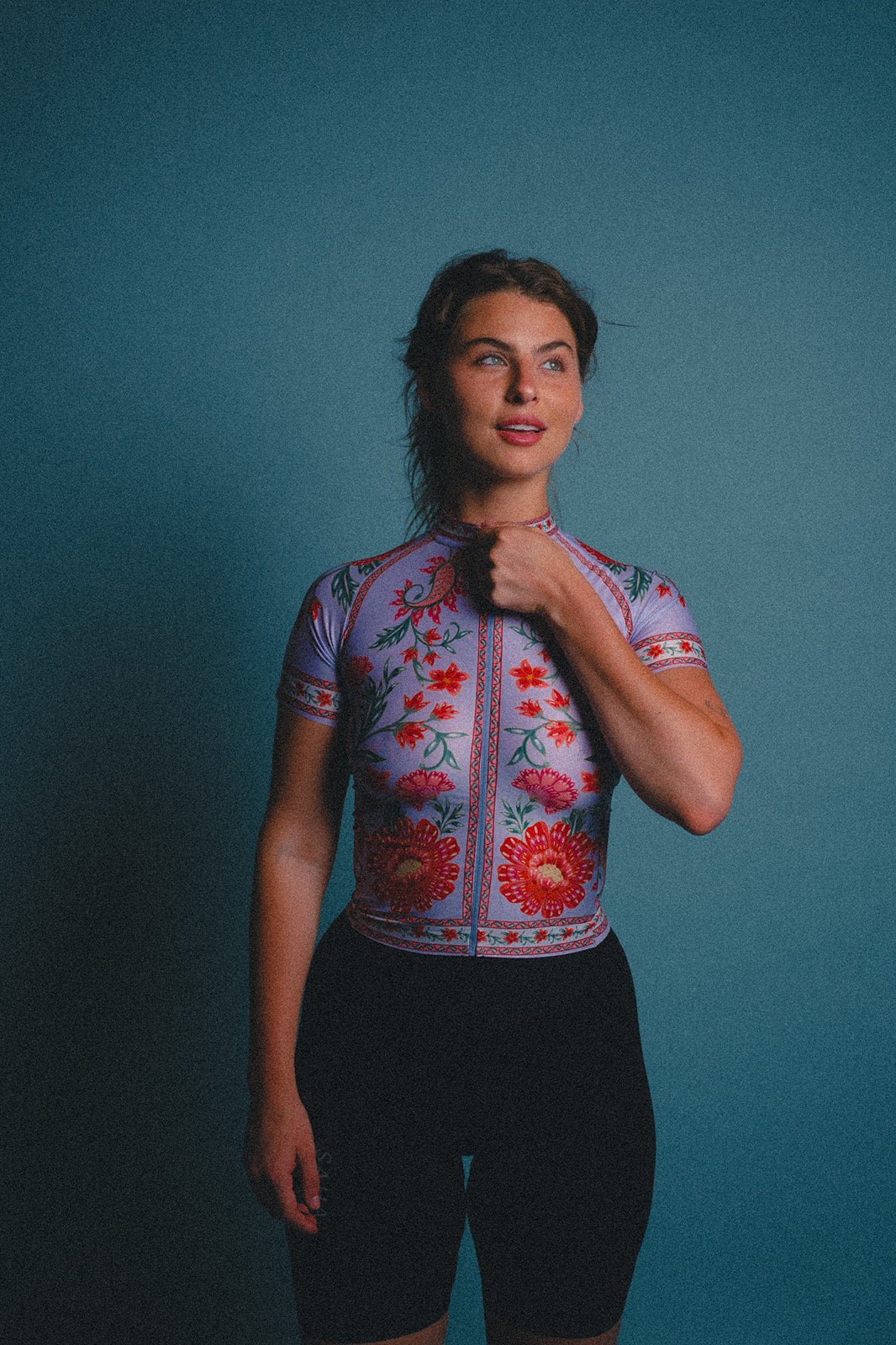 Woman wearing a colorful floral cycling jersey against a blue background