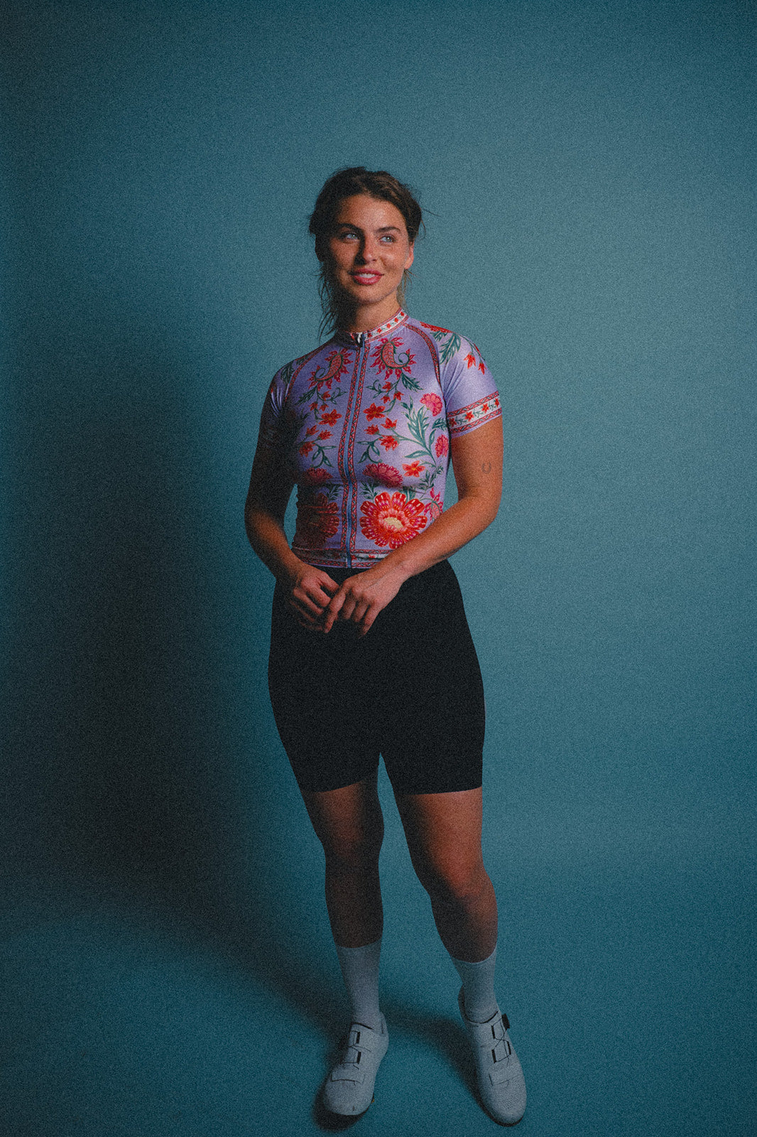 Woman wearing a colorful cycling outfit against a blue background