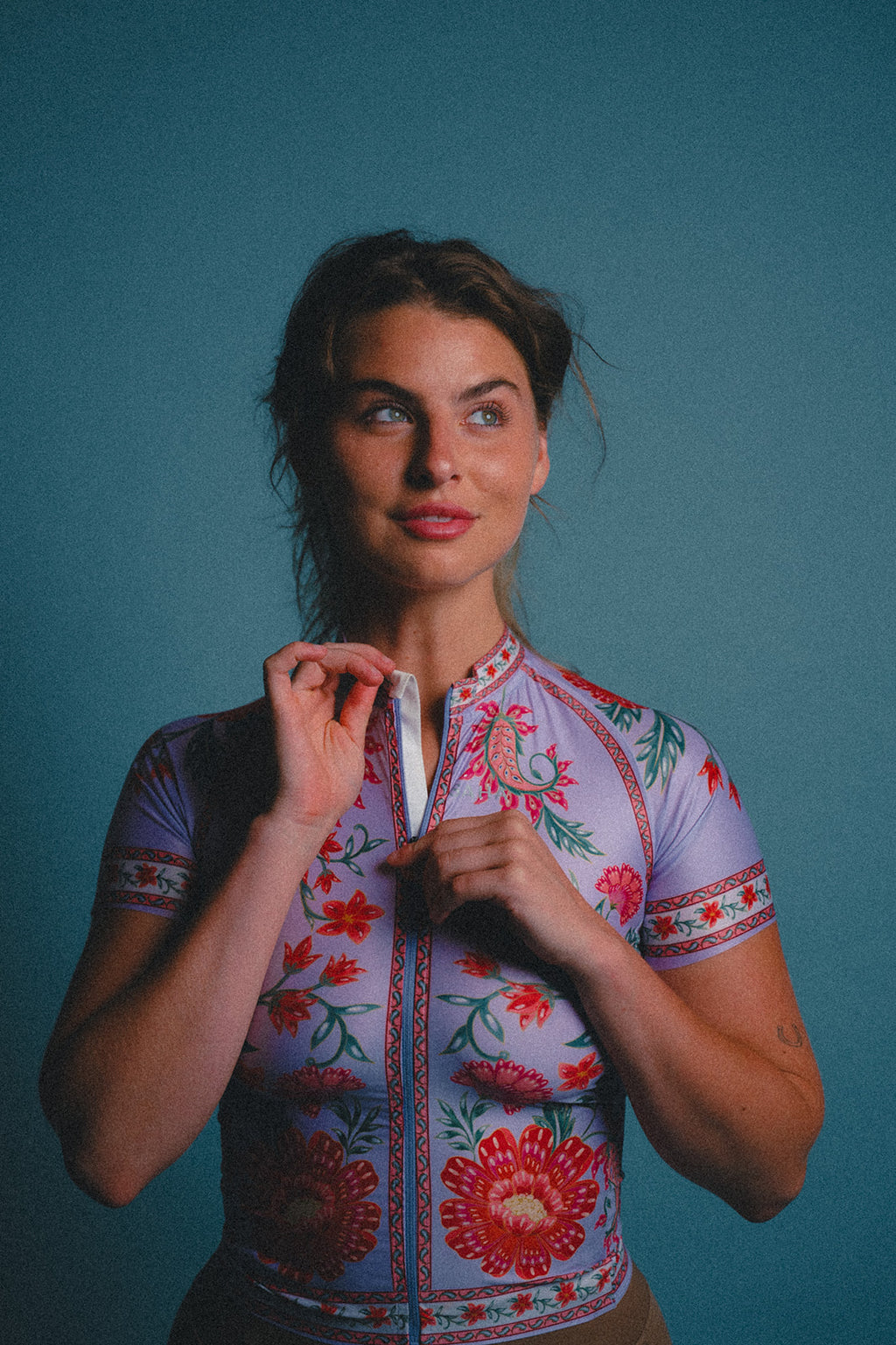 Woman wearing a colorful cycling jersey against a blue background